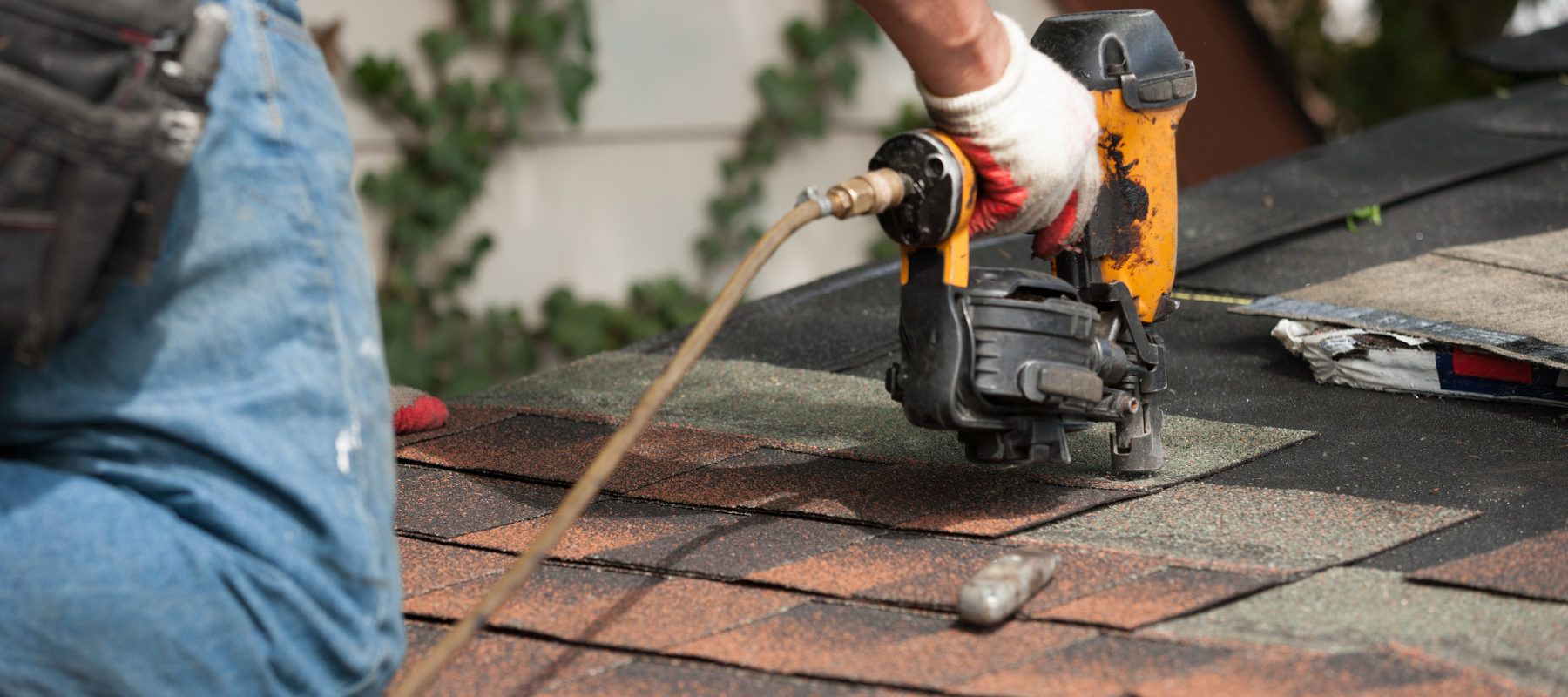 Contractor using a nail gun on a shingle roof